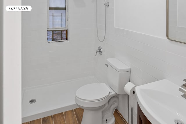 bathroom with sink, tile walls, tiled shower, wood-type flooring, and toilet