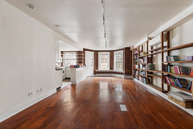 interior space with baseboards, hardwood / wood-style floors, and track lighting