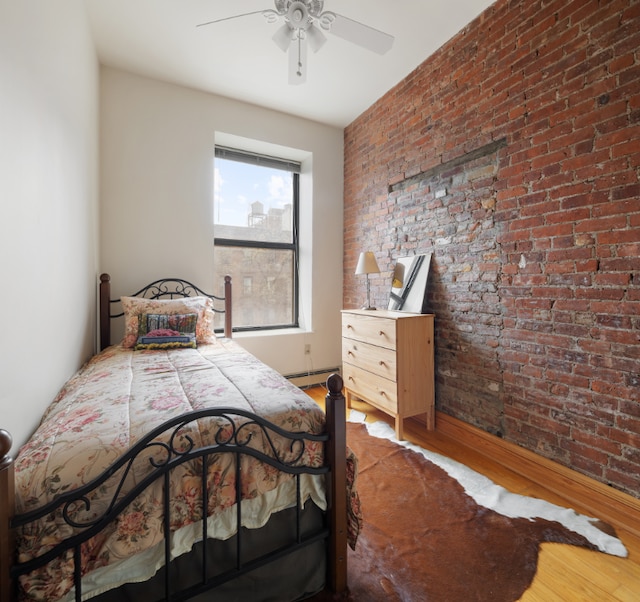 bedroom with hardwood / wood-style flooring, a baseboard radiator, ceiling fan, and brick wall