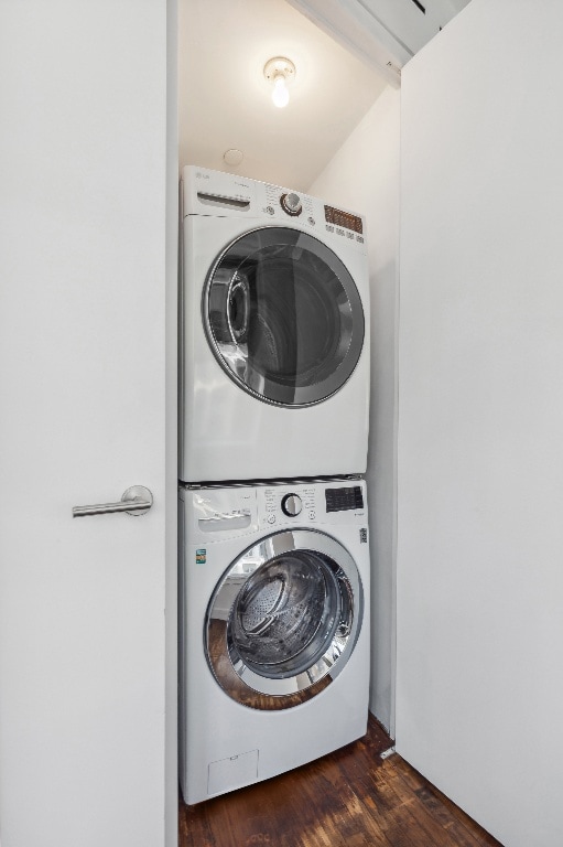 clothes washing area with dark hardwood / wood-style flooring and stacked washer / dryer