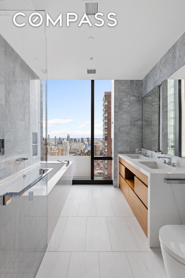 bathroom featuring a bathtub, vanity, toilet, and tile patterned flooring