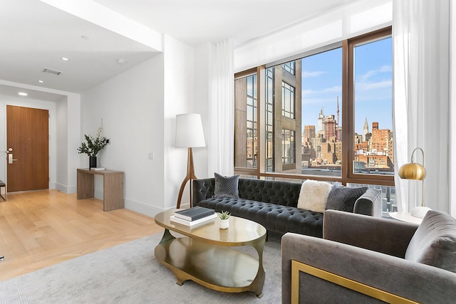 living room featuring recessed lighting, a city view, wood finished floors, visible vents, and baseboards