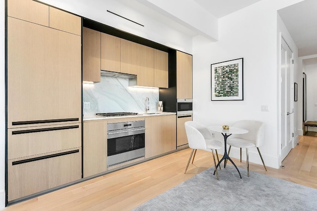 kitchen featuring stainless steel appliances, ventilation hood, light brown cabinetry, decorative backsplash, and light wood-type flooring