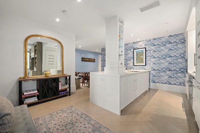 interior space with white cabinetry, kitchen peninsula, and sink