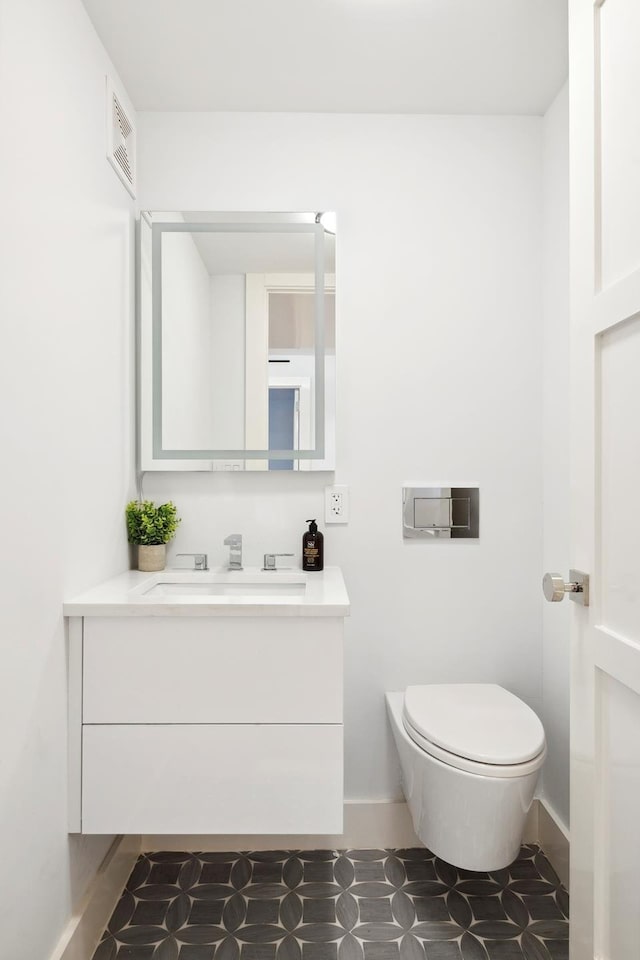 bathroom featuring visible vents, toilet, vanity, and baseboards