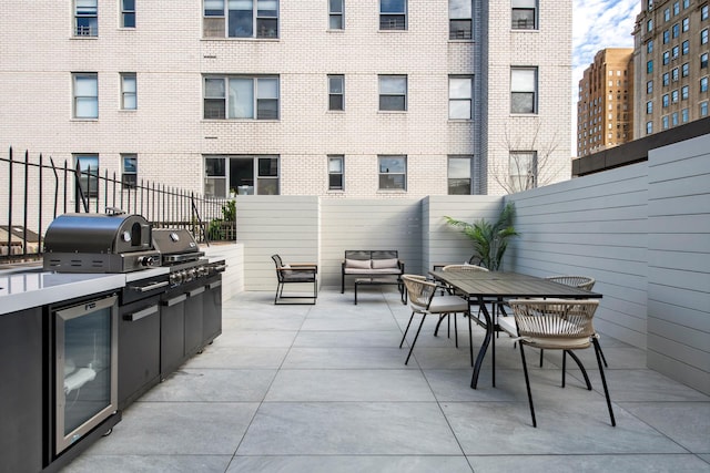 view of patio / terrace with grilling area, beverage cooler, exterior kitchen, and fence