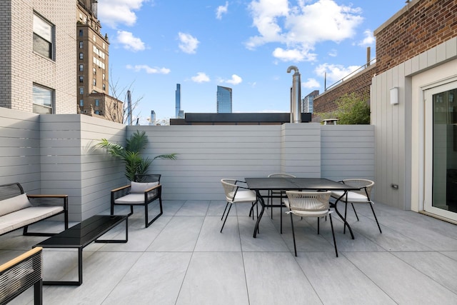 view of patio / terrace featuring a fenced backyard, a view of city, and outdoor dining space