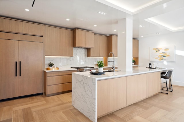 kitchen featuring a spacious island, modern cabinets, tasteful backsplash, and a sink