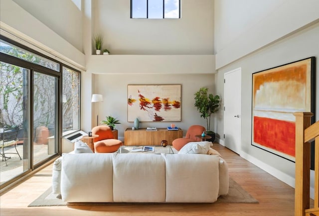 living room with a towering ceiling and hardwood / wood-style flooring