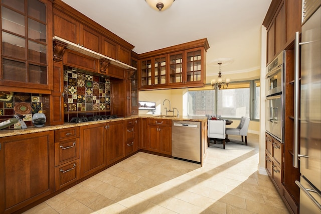 kitchen with black gas stovetop, a sink, stainless steel dishwasher, glass insert cabinets, and pendant lighting