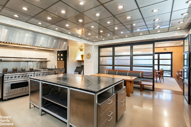 kitchen featuring exhaust hood, a center island, luxury stove, decorative backsplash, and a drop ceiling