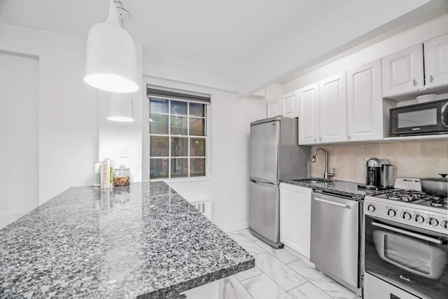 kitchen featuring white cabinets, appliances with stainless steel finishes, decorative light fixtures, sink, and backsplash