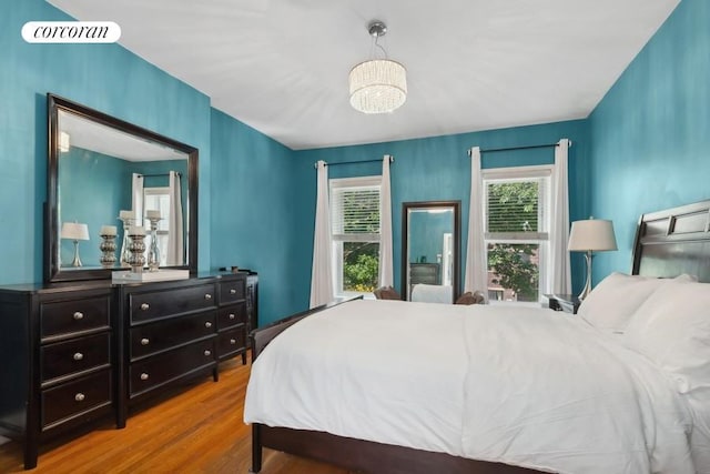 bedroom with a notable chandelier, visible vents, and wood finished floors