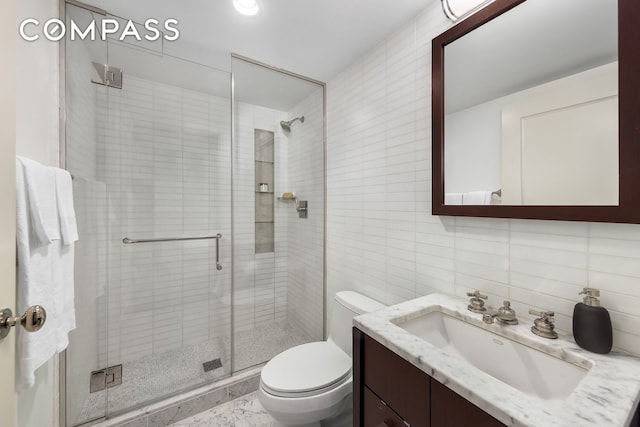 bathroom with tile walls, tasteful backsplash, toilet, a stall shower, and vanity