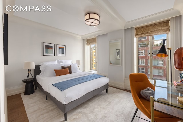 bedroom with baseboards, multiple windows, crown molding, and light wood finished floors