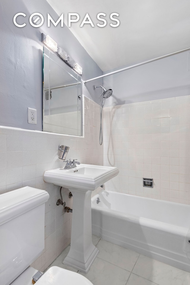 bathroom with toilet, tile walls, and shower / washtub combination