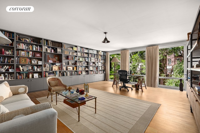 sitting room with bookshelves, wood finished floors, visible vents, and floor to ceiling windows