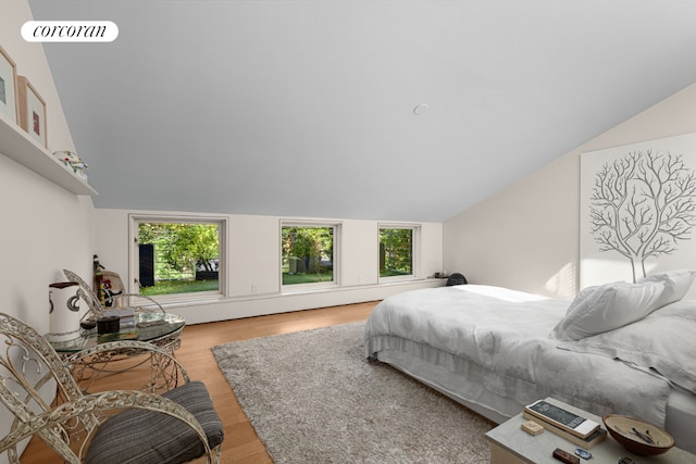 bedroom with lofted ceiling, multiple windows, visible vents, and wood finished floors