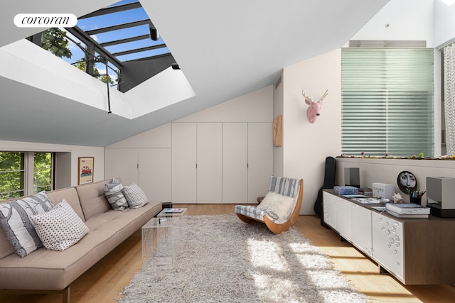 living room with lofted ceiling with skylight, visible vents, and light wood-style flooring