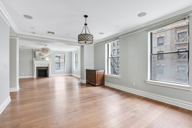 unfurnished living room featuring hardwood / wood-style flooring, a healthy amount of sunlight, and ornamental molding