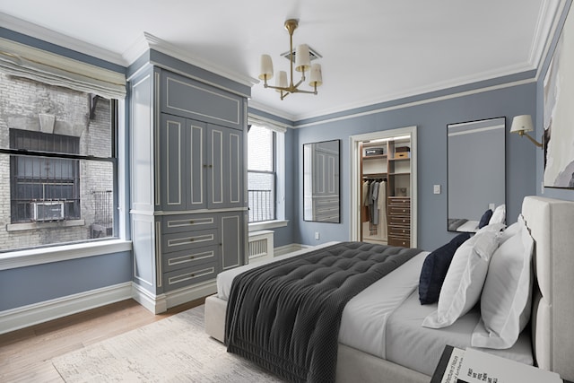 bedroom featuring hardwood / wood-style flooring, a walk in closet, ornamental molding, and an inviting chandelier