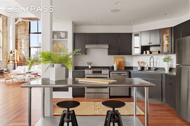 kitchen featuring appliances with stainless steel finishes, sink, a kitchen bar, and light wood-type flooring