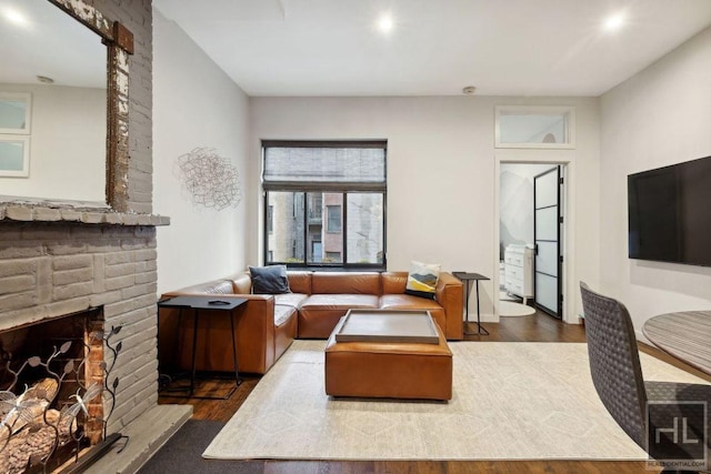 living area with a brick fireplace and wood finished floors