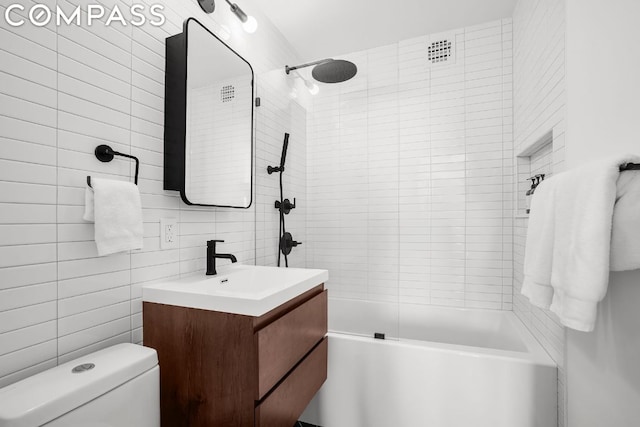 full bathroom featuring toilet, decorative backsplash, tiled shower / bath, tile walls, and vanity