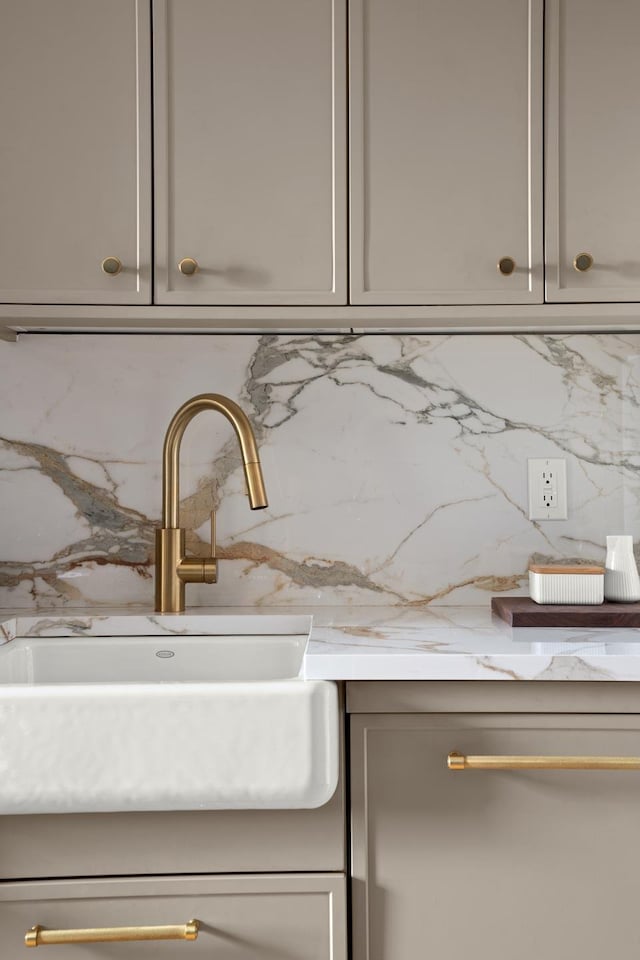 details featuring a sink, light stone countertops, and backsplash