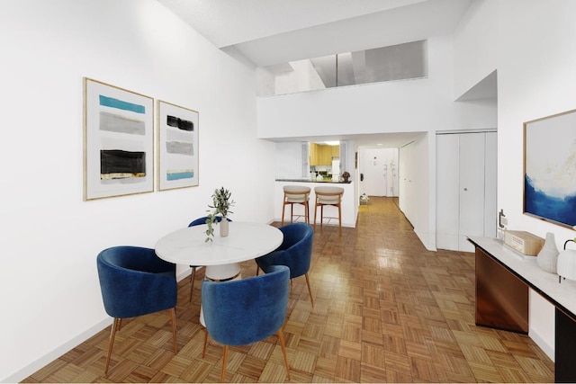 dining room featuring a towering ceiling and light parquet flooring