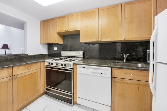 kitchen featuring dark countertops, backsplash, light brown cabinets, white appliances, and a sink