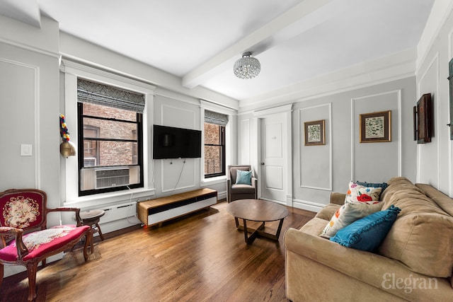 living area with cooling unit, wood finished floors, beam ceiling, and a decorative wall