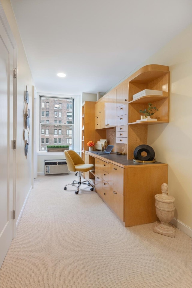 office area featuring baseboards, built in desk, and light colored carpet