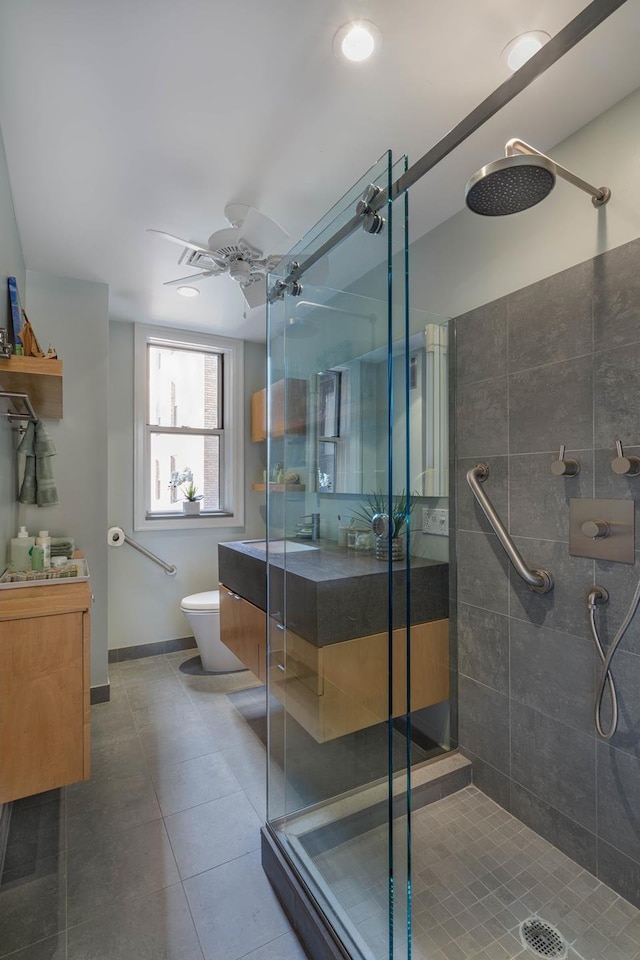 bathroom with tile patterned floors, toilet, a shower stall, ceiling fan, and vanity