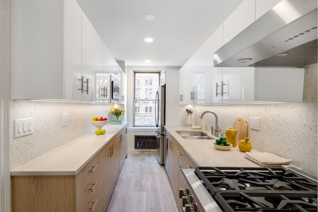 kitchen with light countertops, white cabinetry, a sink, ventilation hood, and modern cabinets