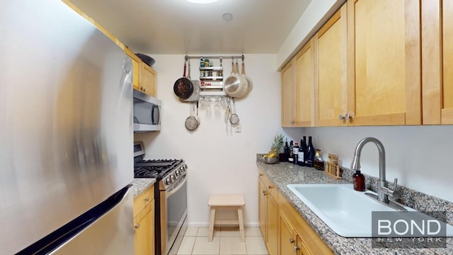 kitchen with light tile patterned floors, stainless steel appliances, light brown cabinets, light stone counters, and sink