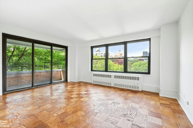 unfurnished room with radiator heating unit and baseboards