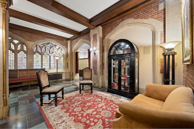 living area with brick wall and beamed ceiling