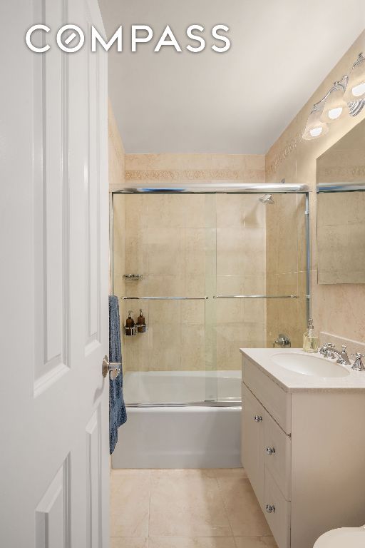 bathroom featuring vanity, tile patterned flooring, and combined bath / shower with glass door