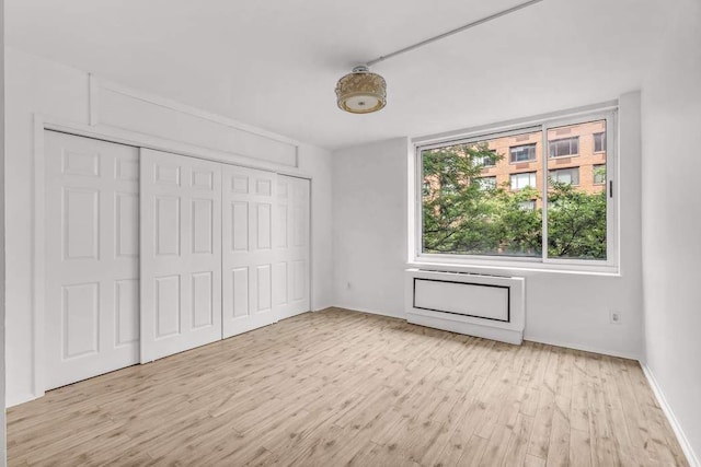 unfurnished bedroom with light wood finished floors and a closet