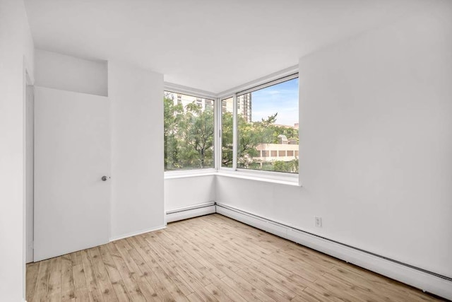 empty room featuring a baseboard heating unit and wood finished floors