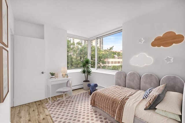 bedroom with a baseboard heating unit and wood finished floors