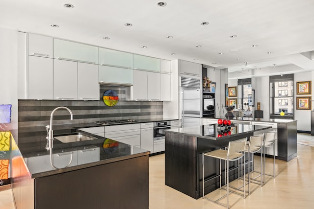 kitchen featuring white cabinets, a center island, a kitchen bar, stainless steel appliances, and sink