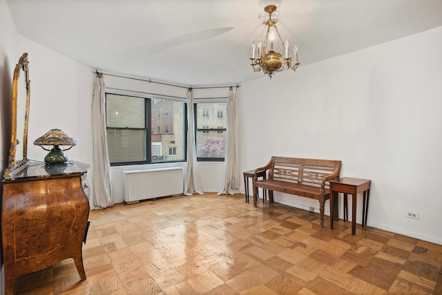 living area featuring radiator, baseboards, and a notable chandelier