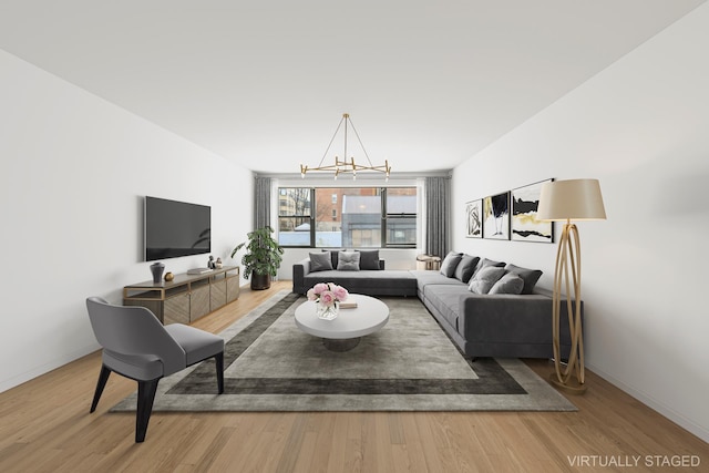 living area with baseboards, an inviting chandelier, and wood finished floors