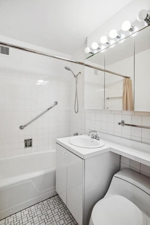 full bathroom with tasteful backsplash, tiled shower / bath, tile walls, vanity, and toilet