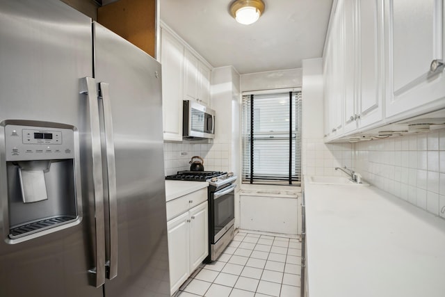 kitchen with light countertops, appliances with stainless steel finishes, white cabinets, a sink, and light tile patterned flooring