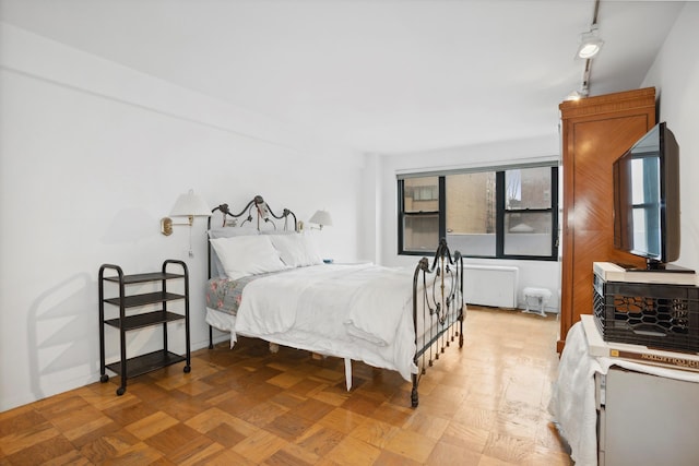 bedroom featuring rail lighting and baseboards