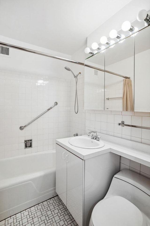 bathroom with toilet, tile walls, vanity, tile patterned floors, and tasteful backsplash