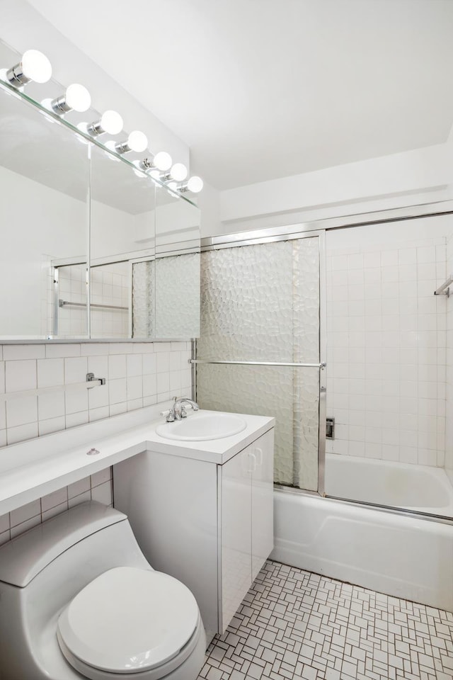 full bath featuring enclosed tub / shower combo, toilet, vanity, tile walls, and decorative backsplash